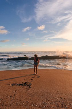 Sahilde dalgaların arasında duran genç bir kadın.