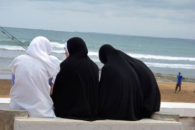 ,Atlantic, Essauria, Fas yakınındaki bir bankta örtülü Müslüman kadın                                                      