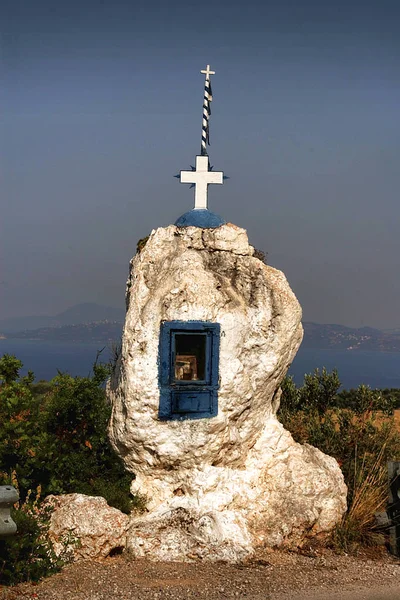 Cross on a big boulder by road, Greece