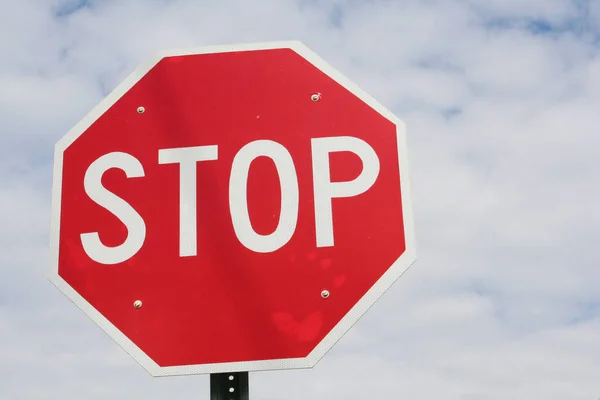 Parlak kırmızı dur işaretini yüksek beyaz bulutlar çevreleyen mavi gökyüzü.
