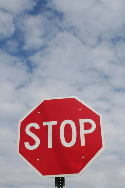 Parlak kırmızı dur işaretini yüksek beyaz bulutlar çevreleyen mavi gökyüzü.