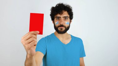 Kırmızı kart tutan hayran. Uruguay makyaj yüzünde ve mavi t-shirt bayrağı olan adam                               