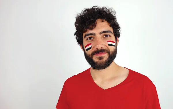 Sport fan smiling looking at camera. Man with the flag of Egypt makeup on his face and red t-shirt.
