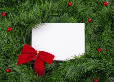 Yaratıcı Noel düzeni. Beyaz kart kopya alanı yeşil tinsel ve kırmızı kurdele ve topları ile. Kenarlık düzenleme. Düz yatıyordu üstten görünüm.