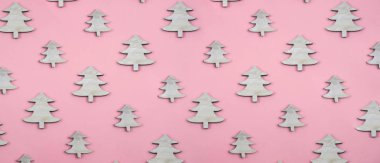 Ahşap noel ağaçlarından yapılmış yaratıcı ve minimal Noel deseni. Pembe arka plan. Düz lay üst görünüm.