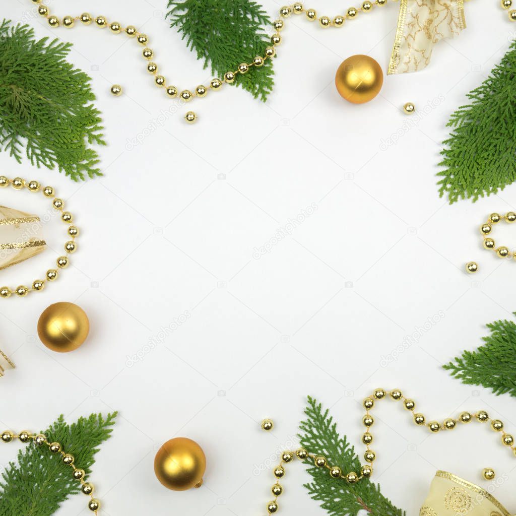 Creative Christmas layout. Golden balls and green twigs on white background whit copy space. Border arrangement. Flat lay top view.