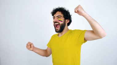 Spor taraftarı takımının zaferi için bağırıyor. Yüzünde Ekvador makyaj ve sarı t-shirt bayrağı ile Adam.