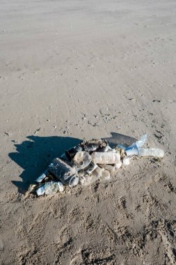 Okyanus çöplerinden yapılmış plaj kumu üzerinde yatan balık şekli. Plastik kirlilik kavramı.