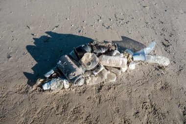 Okyanus çöplerinden yapılmış plaj kumu üzerinde yatan balık şekli. Plastik kirlilik kavramı.