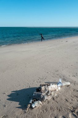 Okyanus çöplerinden yapılmış plaj kumu üzerinde yatan balık şekli. Plastik kirlilik kavramı.