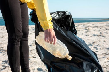 Çöp ve plastik toplayan kadın çöp torbasıyla plajı temizliyor. İklim değişikliği ve okyanusların kirliliğine karşı çevre gönüllü aktivisti.
