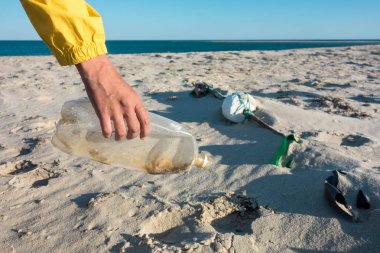 Çöp ve plastik toplayan kadın çöp torbasıyla plajı temizliyor. İklim değişikliği ve okyanusların kirliliğine karşı çevre gönüllü aktivisti.