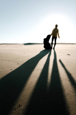 Çöp ve plastik toplayan kadın çöp torbasıyla plajı temizliyor. İklim değişikliği ve okyanusların kirliliğine karşı çevre gönüllü aktivisti.