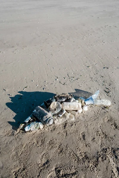 Okyanus çöplerinden yapılmış plaj kumu üzerinde yatan balık şekli. Plastik kirlilik kavramı.