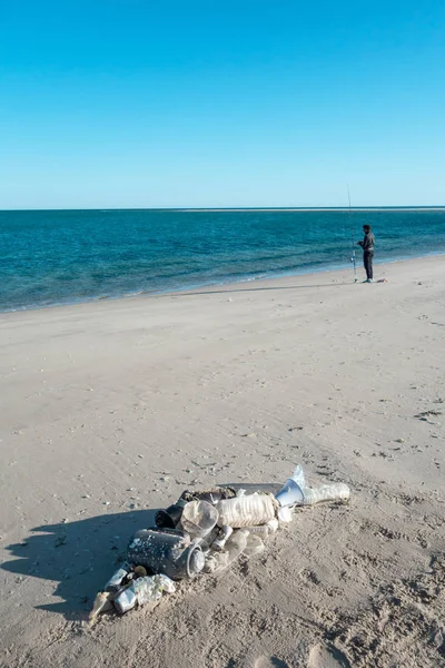 Okyanus çöplerinden yapılmış plaj kumu üzerinde yatan balık şekli. Plastik kirlilik kavramı.