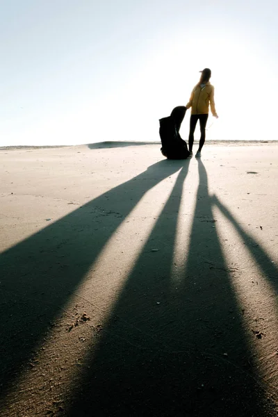 Çöp ve plastik toplayan kadın çöp torbasıyla plajı temizliyor. İklim değişikliği ve okyanusların kirliliğine karşı çevre gönüllü aktivisti.