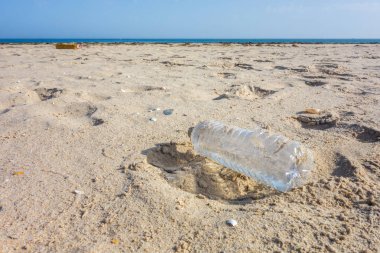Kum kumundaki plastik şişe. Okyanuslar kavramının plastik kirliliği.