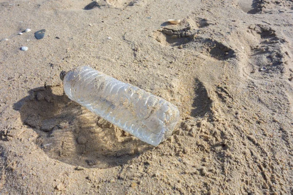 Plastic bottle on the beach sand. Plastic pollution of the oceans concept.