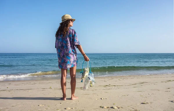 Woman picking up trash and plastics cleaning the beach. Environmental volunteer activist against climate change and the pollution of the oceans.