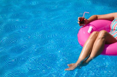 Mavi havuzda mayo giymiş genç bir kadın. Bir kokteyl içerken yaz zevk pembe bir şamandıra üzerinde Pretty kız.