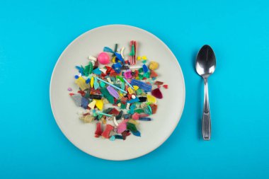 Plate full of microplastics. Plastic pollution concept. clipart