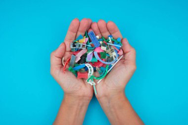 Hands full of microplastics collected on the beach. Plastic pollution concept. clipart