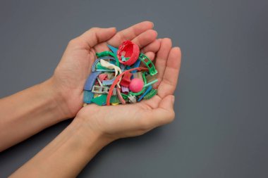 Elleri plajda toplanan mikroplastiklerle dolu. Plastik kirliliği kavramı.