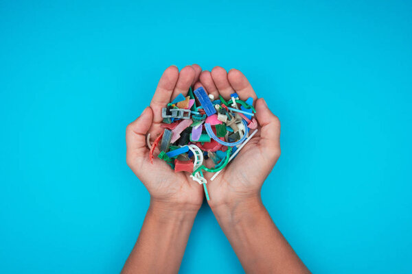 Hands full of microplastics collected on the beach. Plastic pollution concept.