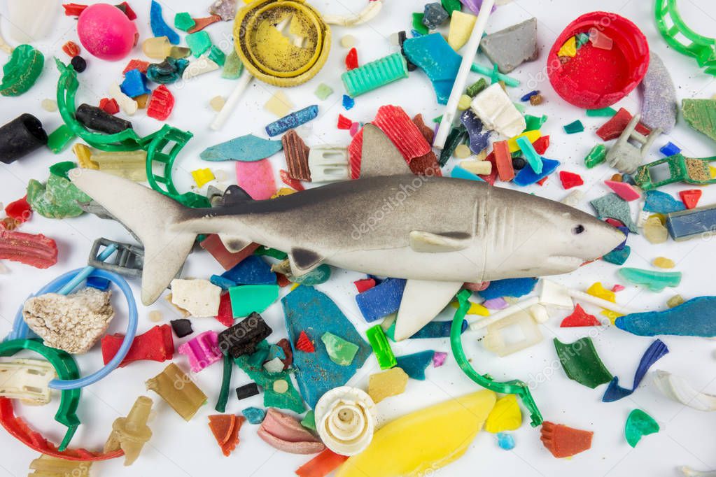 Toy shark over microplastics collected on the beach. Plastic pollution concept.