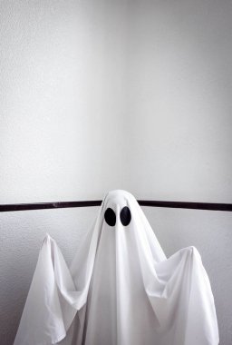 Ghost covered with a white ghost sheet on the stairs of an abandoned psychiatric hospital. Halloween Concept clipart