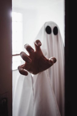 Ghost covered with a white ghost sheet behind the door. Halloween Concept