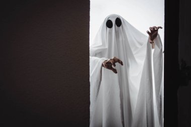Ghost covered with a white ghost sheet behind the door. Halloween Concept
