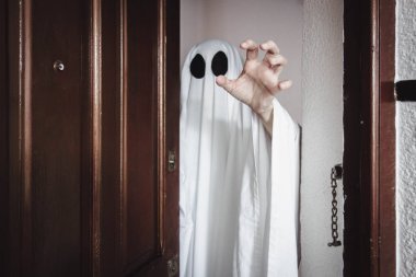 Ghost covered with a white ghost sheet behind the door. Halloween Concept