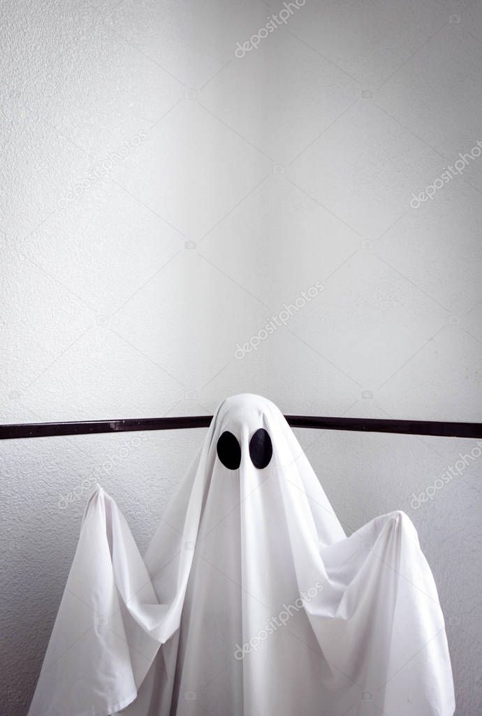 Ghost covered with a white ghost sheet on the stairs of an abandoned psychiatric hospital. Halloween Concept