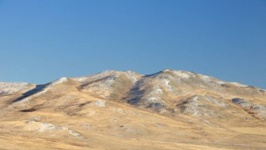 Kış manzarası ile pürüzsüz bir tepe ile sarı bir kuru ot kaplı ve ilk Khakassia, Rusya'da koyu mavi gökyüzü altında kar