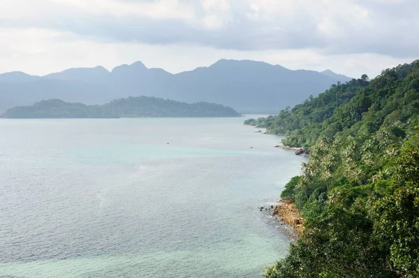 Bird eye view of tropical landscape with stone coastline, coconut palm trees, rainforest, tropical sea and mountains on tropical Koh Chang island in Trat province of Thailand