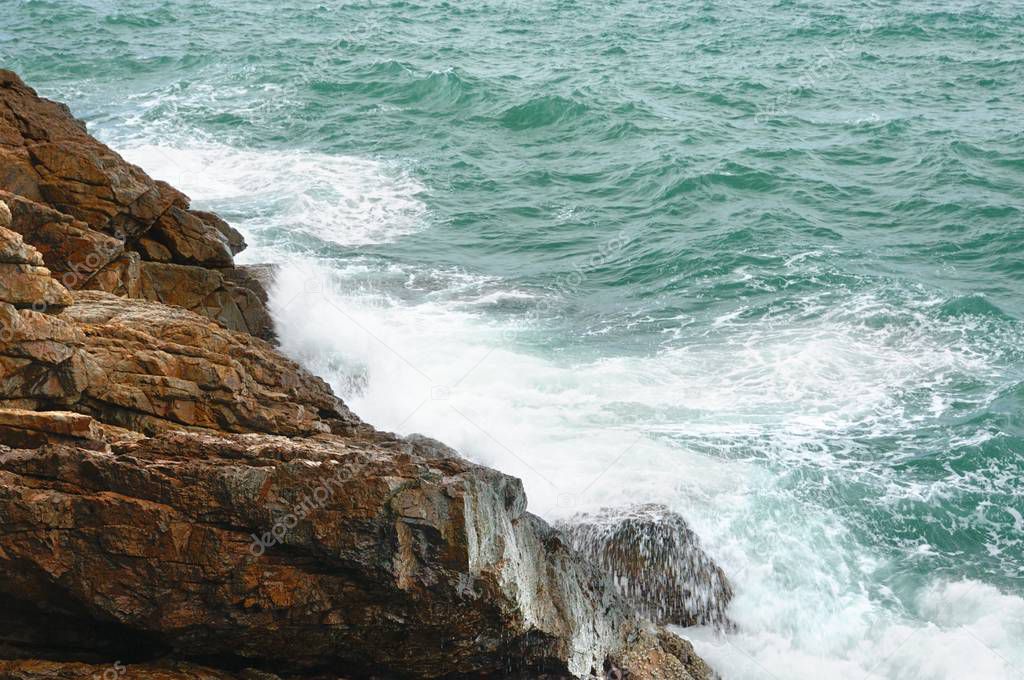 View of deserted rocky coastline and turquoise tropical storm sea with a surf on tropical Koh Chang island in Trat province of Thailand