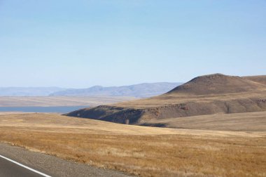 Khakassia, Rusya'nın mavi gökyüzü altında Kuru sarı çim kaplı pürüzsüz hills, sonbahar yatay