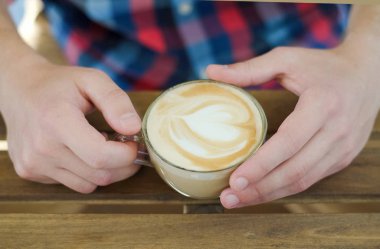 Mens hands holding a Cup of cappuccino clipart