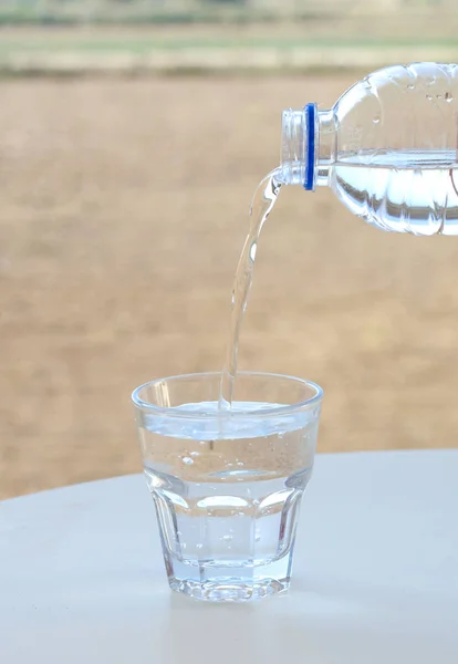 Καθαρό νερό ρέει από το μπουκάλι στο ποτήρι. — Φωτογραφία Αρχείου