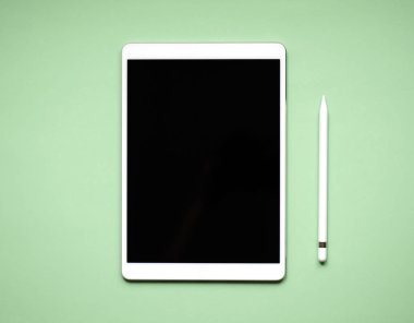 Sağlam yeşil bir arka plan üzerinde beyaz tablet yalan.