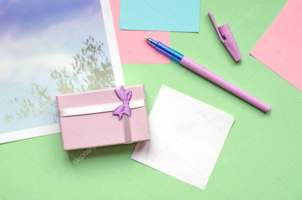 A small gift of pale lilac. Office, stickers, pen on a green background.