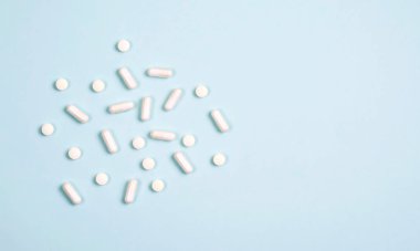 Mavi bir arka plan üzerinde beyaz tabletler farklı vitamin.