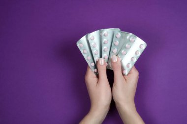 Mor bir arka plan üzerinde beyaz tabletler çeşitli vitamin