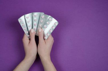 Mor bir arka plan üzerinde beyaz tabletler çeşitli vitamin