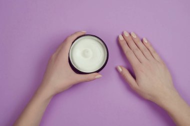 Lila bir arka plan üzerinde bir kavanoza nemlendirici vücut kremi
