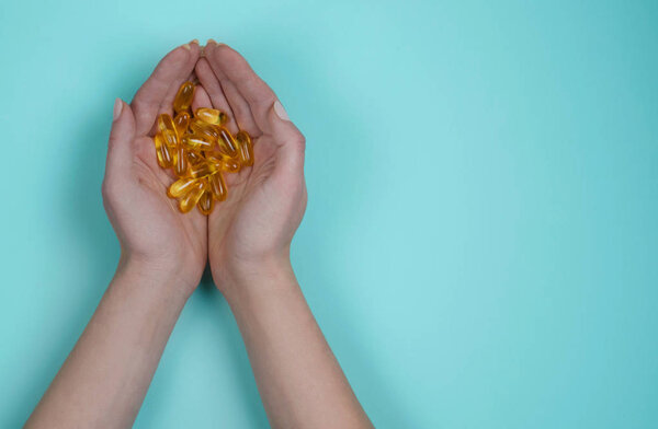 Yellow fish oil in tablets on blue background. Vitamins