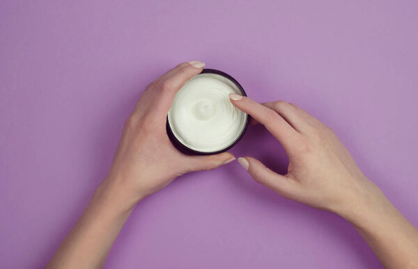 Moisturizing body cream in a jar on a lilac background