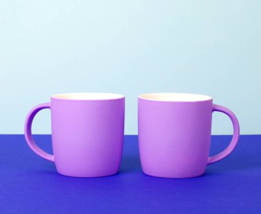 Bright new cups on a solid pastel background. clipart