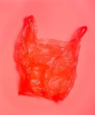 Açık kırmızı arka plan üzerinde parlak kırmızı plastik torba.